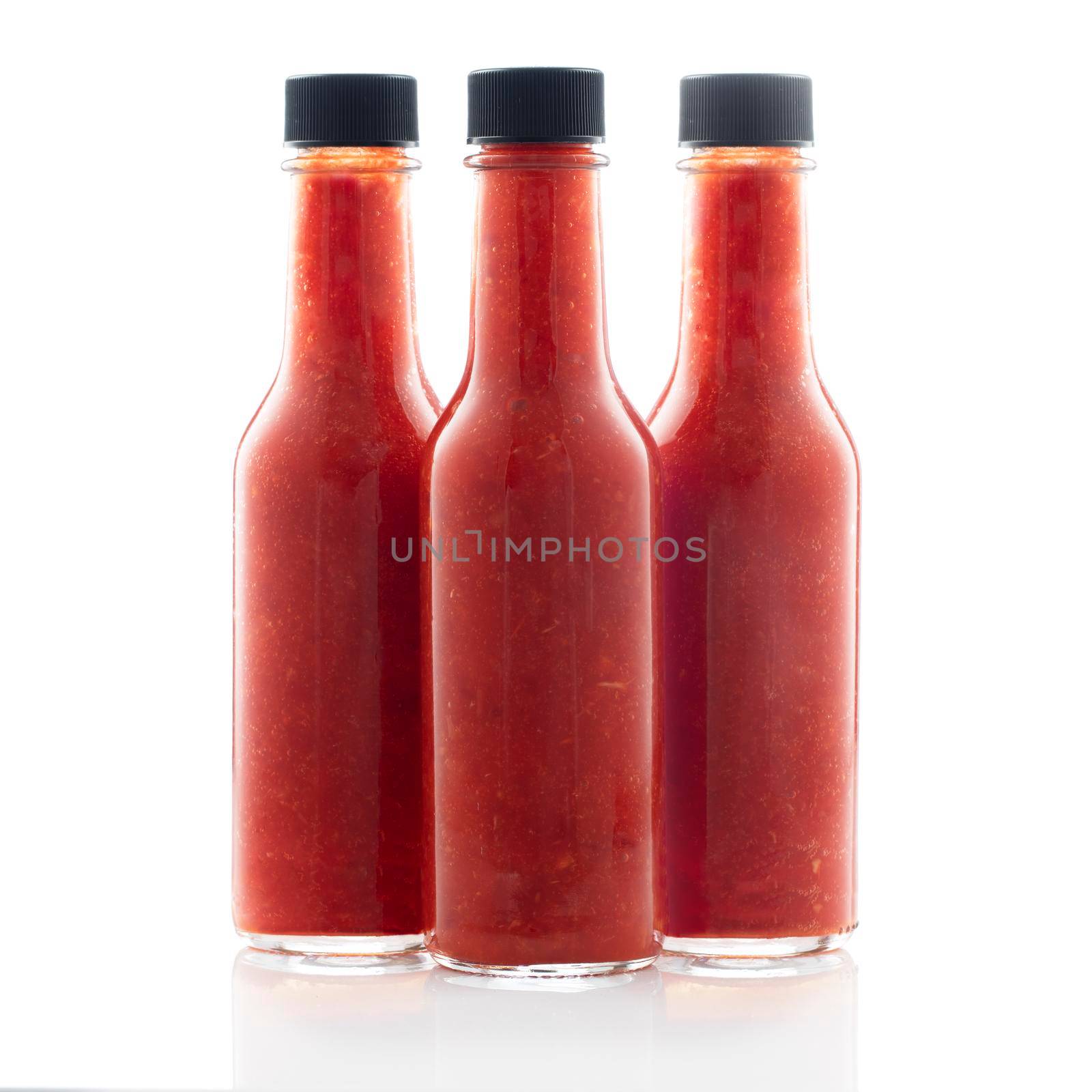 Three bottles of hot sauce without lables isolated on a white background.