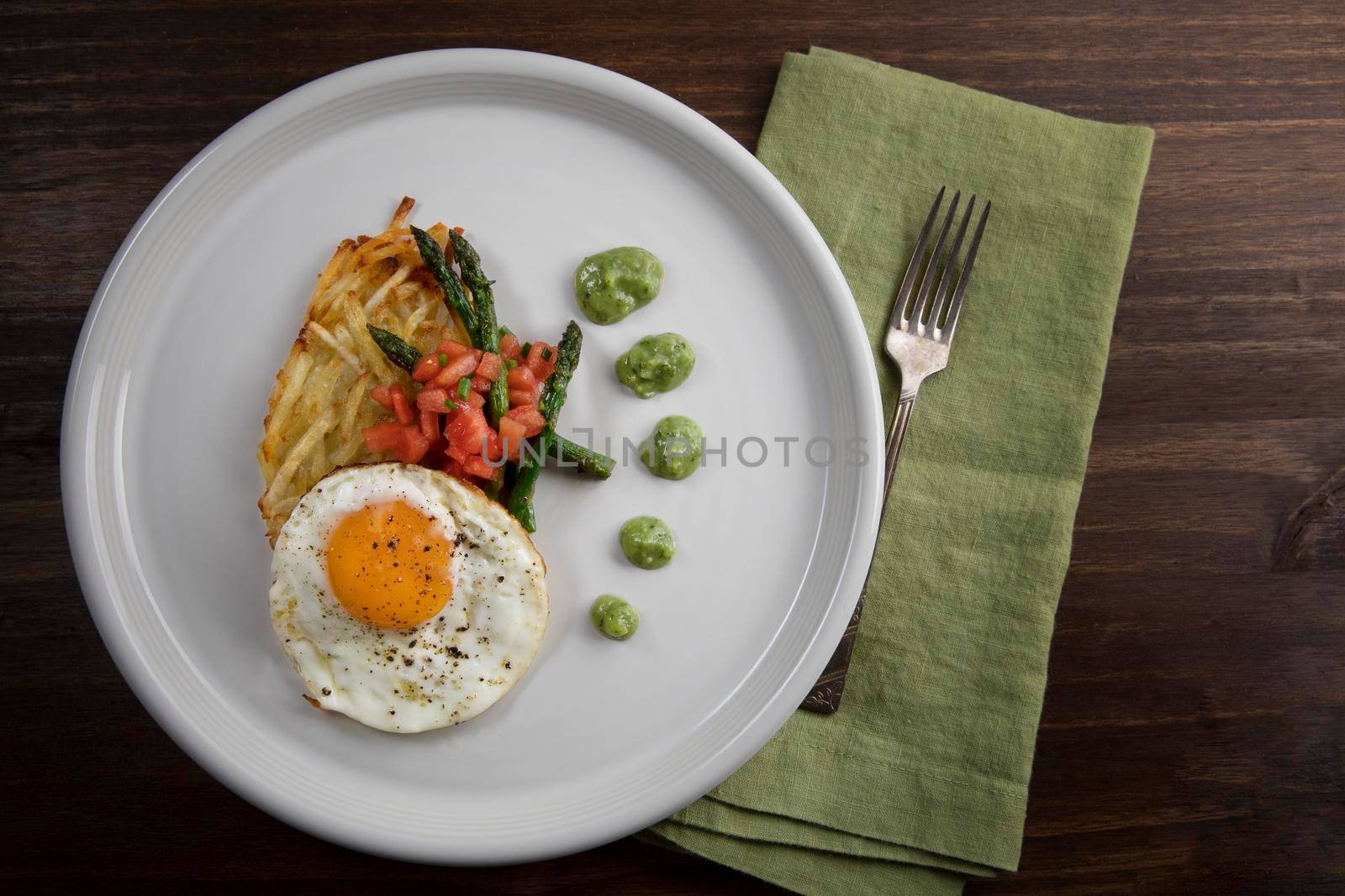 Fried egg with hashbrowns, asparagus, tomatoes and avocado sauce.