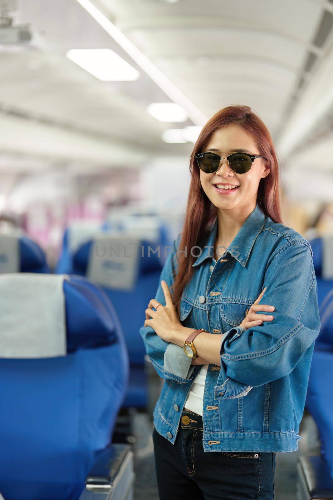 Portrait of an Asian woman taking a selfie or capturing memories while waiting for an economy class flight. Travel concept, vacations, tourism by Manastrong