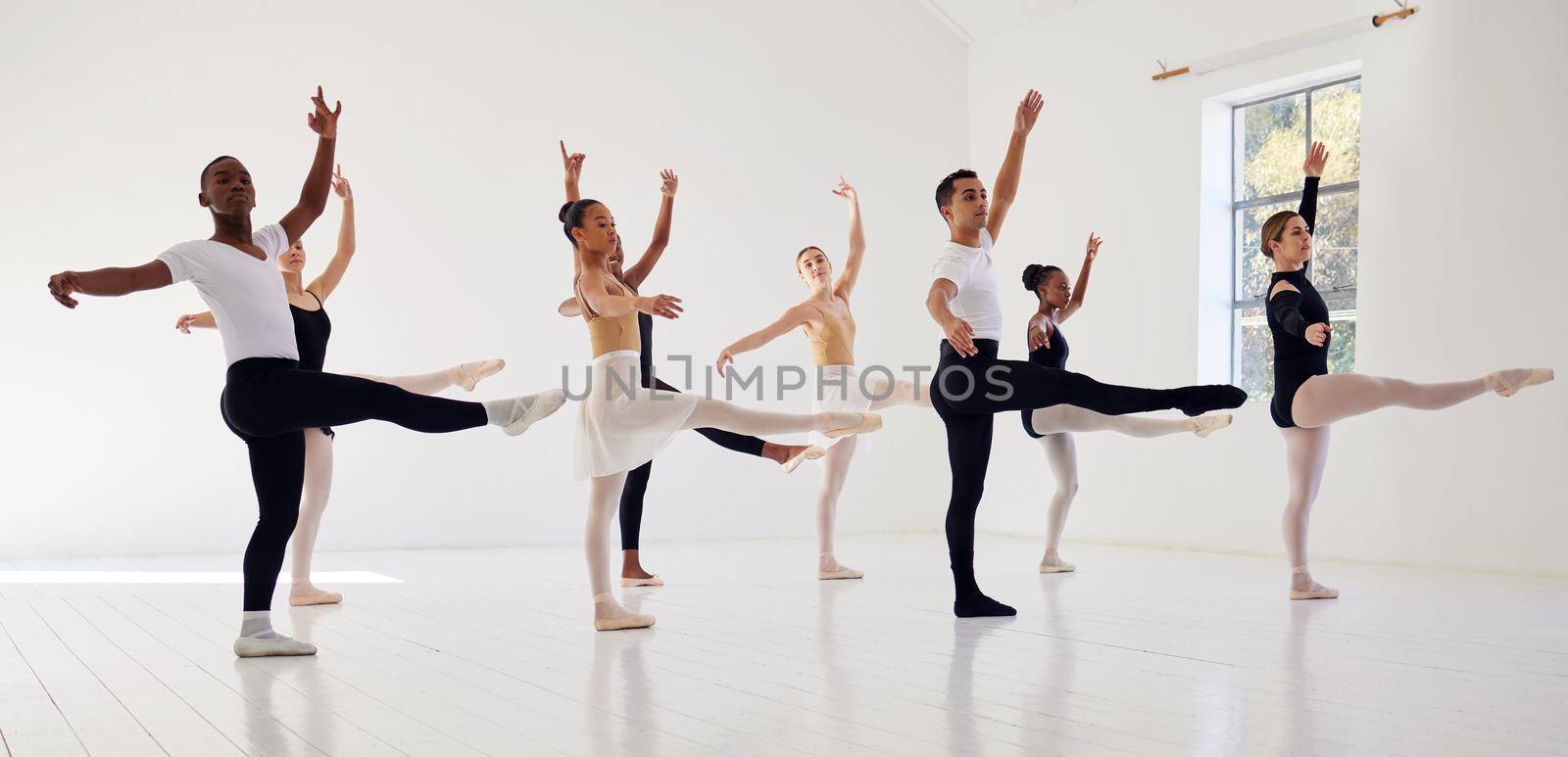 Dancing is the poetry of the foot. a group of ballet dancers practicing a routine in a dance studio. by YuriArcurs