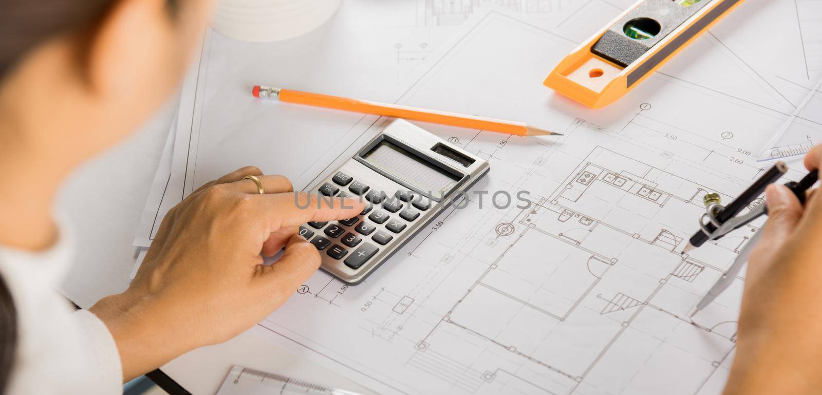 Architectural project workplace. Architect drawing with divider compass on house plan blueprint paper for repair tools on table desk at architecture office, Engineer sketching construction project