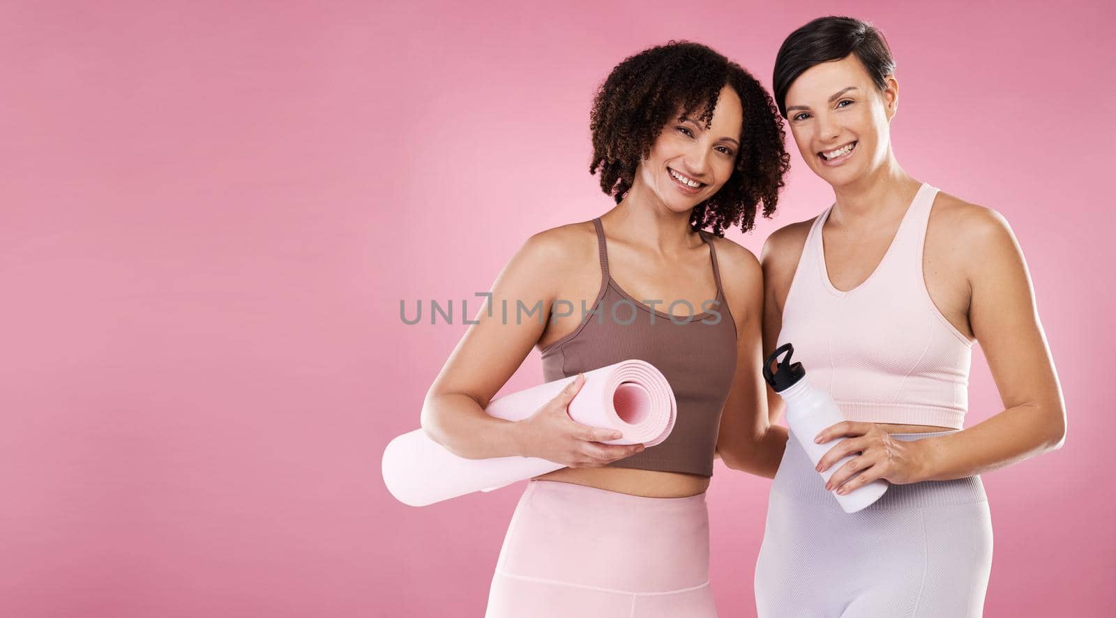 Weve got a passion for yoga. Cropped portrait of two attractive young female athletes posing in studio against a pink background. by YuriArcurs