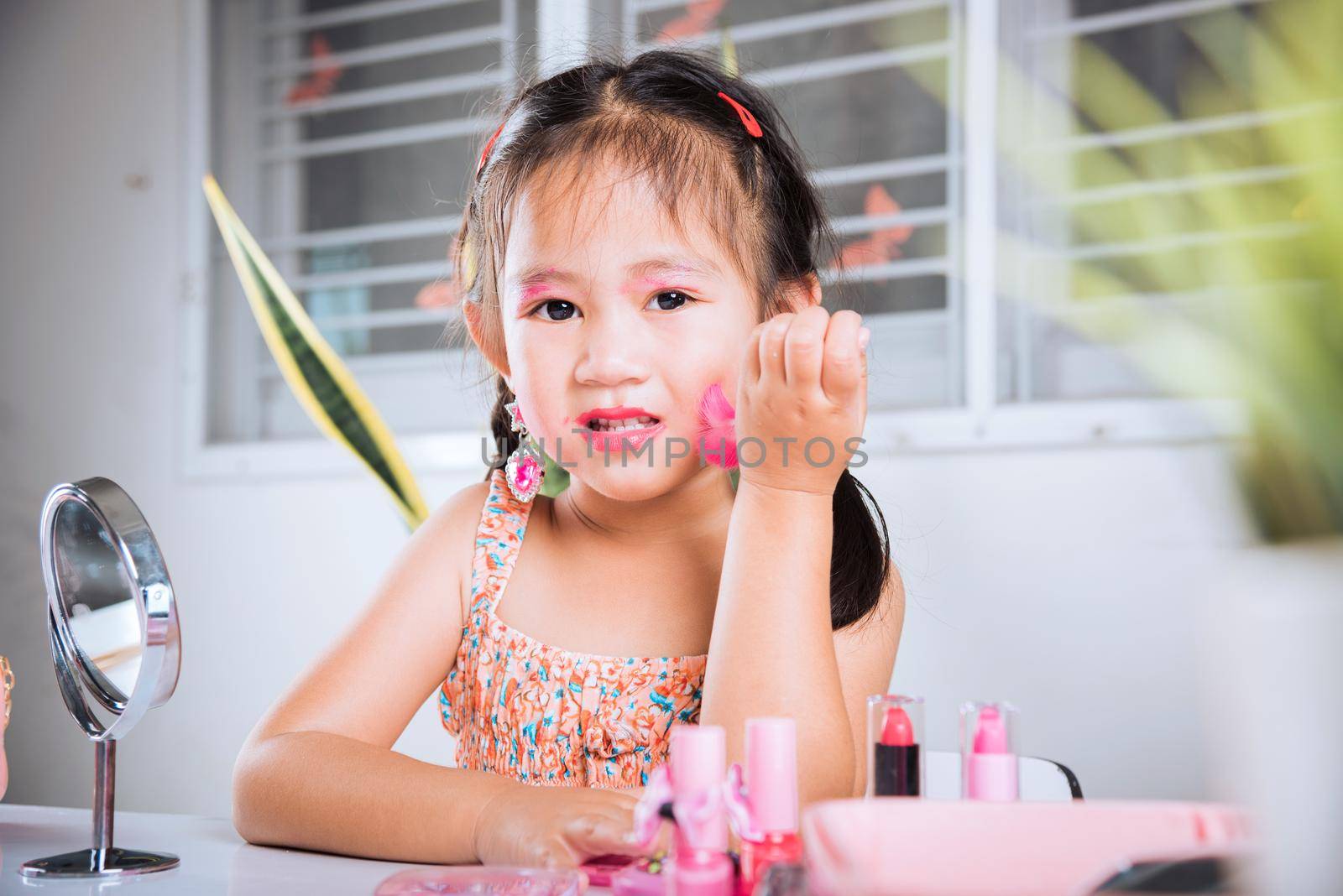 Happy kid is beautiful make up with cosmetics toy, Asian adorable funny little girl making makeup her face she looking in the mirror and cheek fluffy brush for powder, Learning activity to be woman