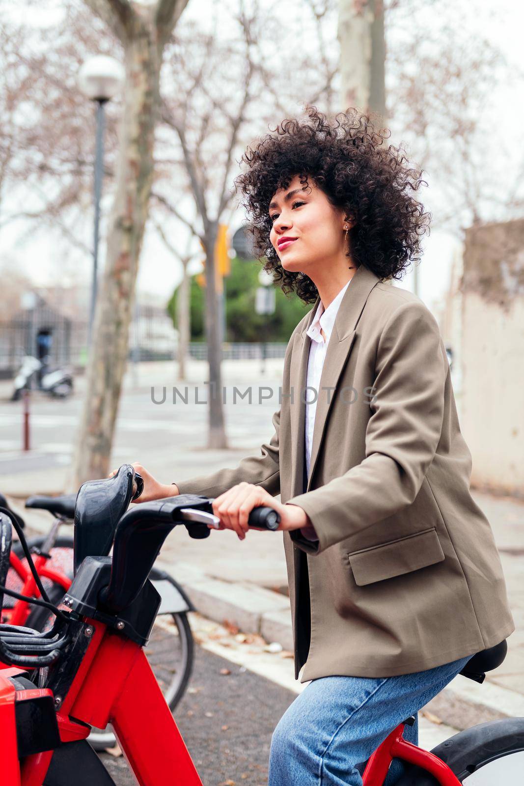 young latin woman rides an electric bike from a rental station, active lifestyle and sustainable mobility concept
