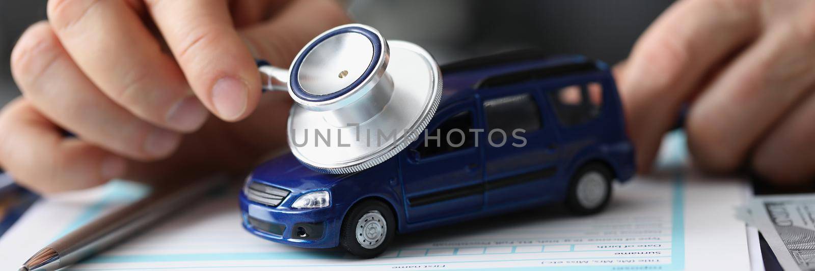 Close-up of man use car with stethoscope tool, symbol of car insurance or maintenance service. Protect automobile with insurance. Checkup, repair concept