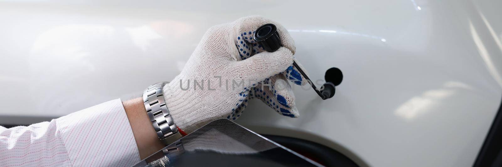 Close-up of male automechanic holding modern digital tablet and car tube in white gloves. Mechanic worker at service station. Automotive check, fix concept