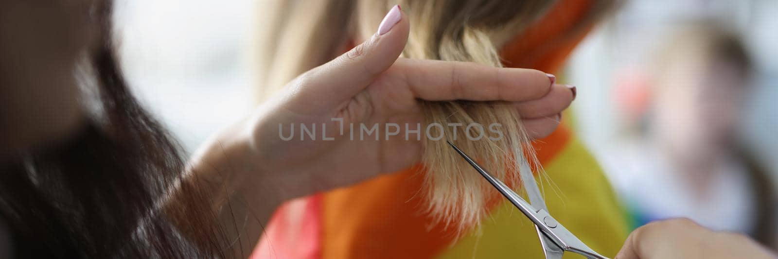 Woman holding lock of hair and cutting with scissors equipment by kuprevich