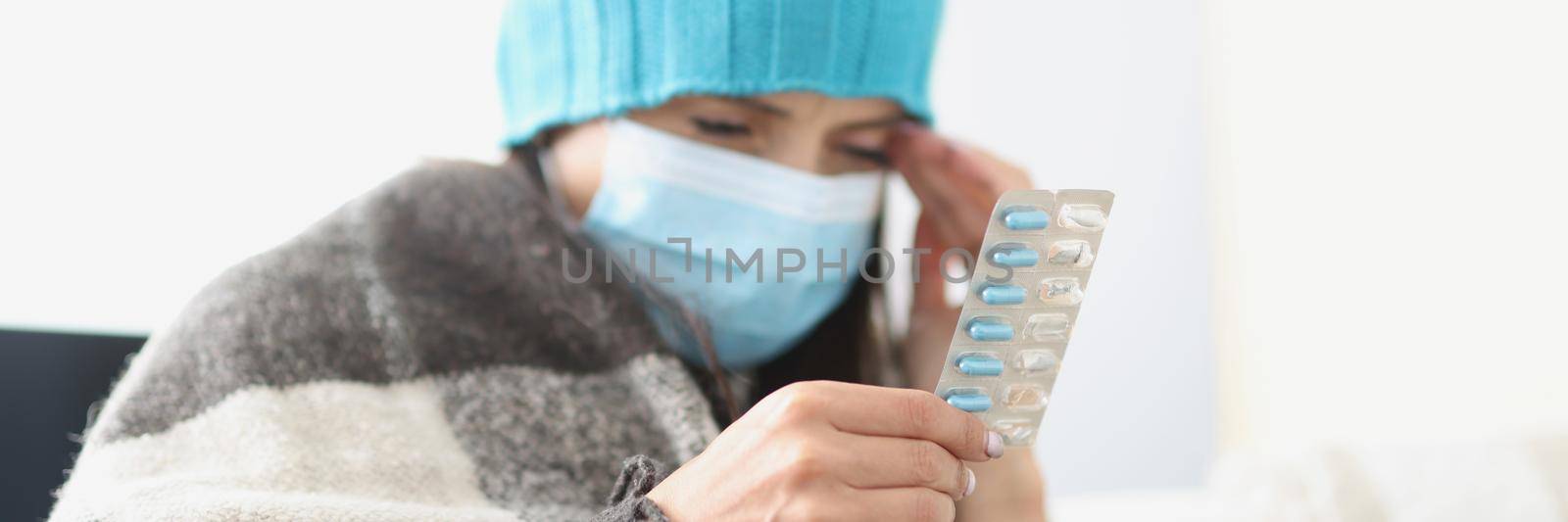 Portrait of woman hold blister with tablets in hand, feeling unwell, bad headache. Female on quarantine at home, self isolation. Health, sickness concept