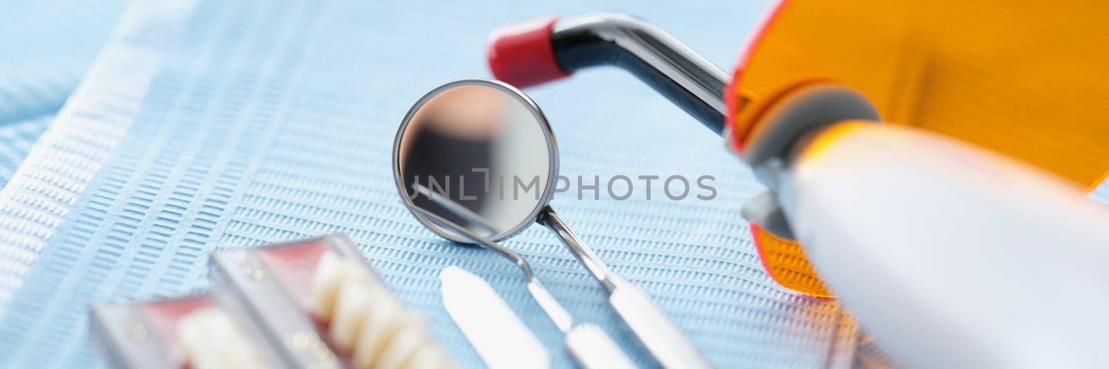 Close-up of set of dentist medical tools for cure people teeth. Whitening instrument, tiny mirror, teeth sample on surface. Stomatology cabinet concept