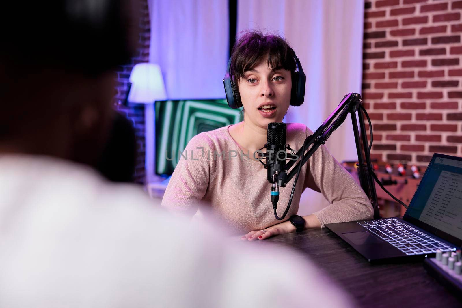 Lifestyle blogger having conversation with female guest, recording podcast with sound equipment. Influencer talking to cheerful woman to broadcast live discussion to record in studio.