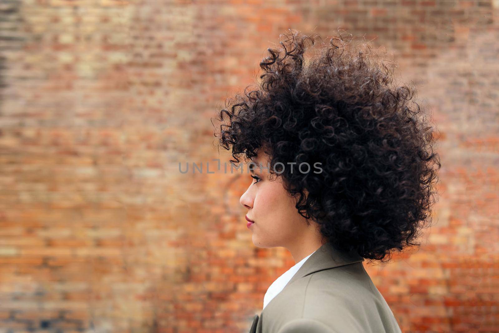 profile portrait of a young latin woman with curly hair, copy space for text