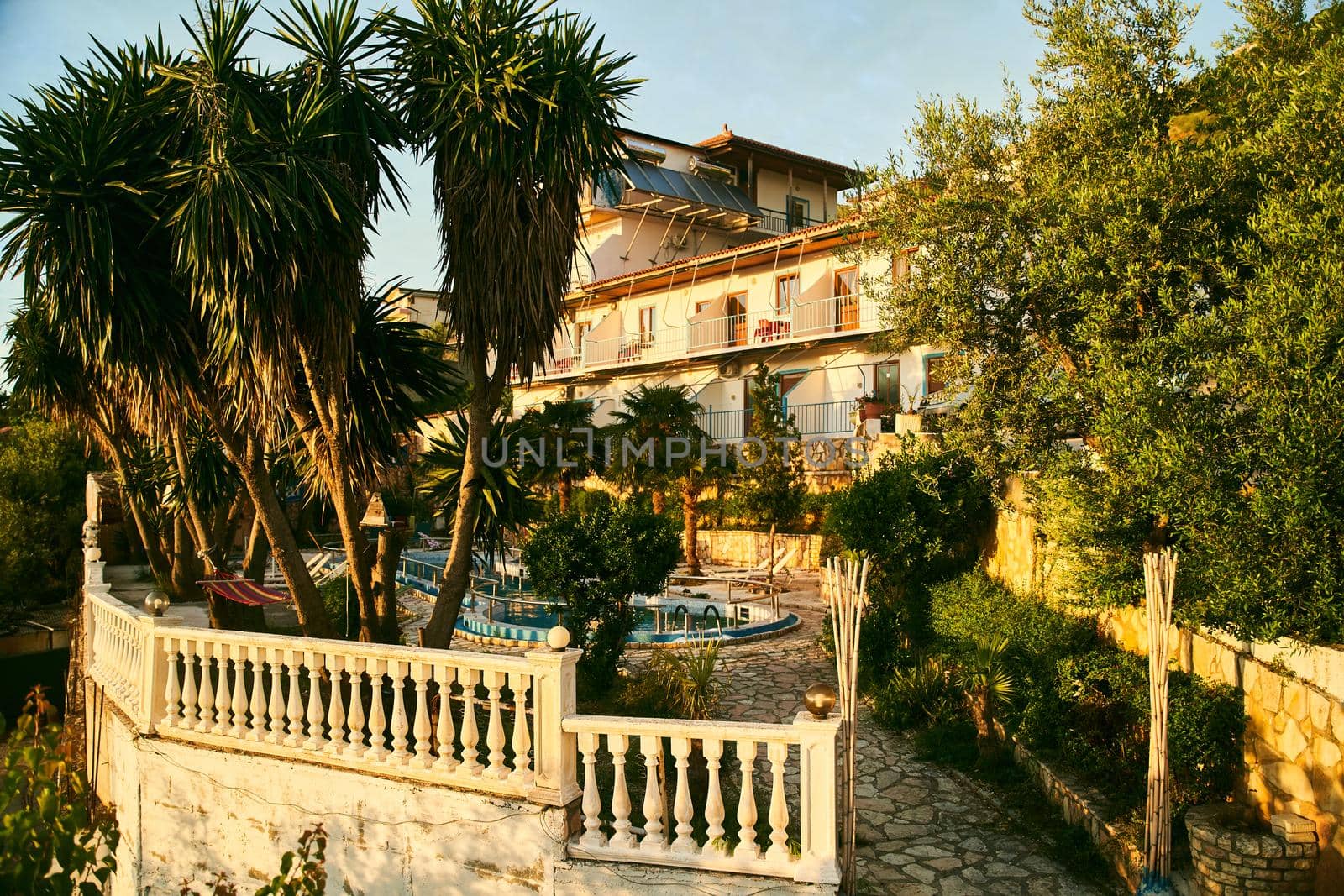 A small hotel with a swimming pool and palm trees in Albania. High quality photo