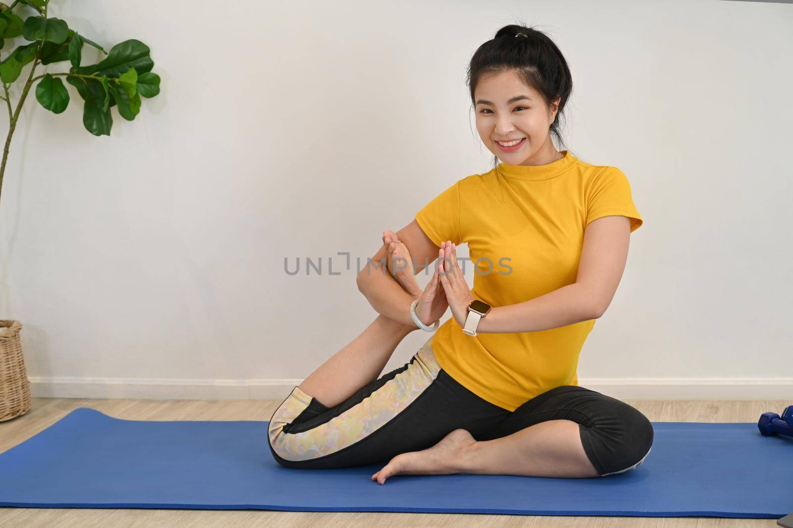 Young healthy woman practicing yoga on mat at home. Mindfulness meditation, healthy lifestyle concept.