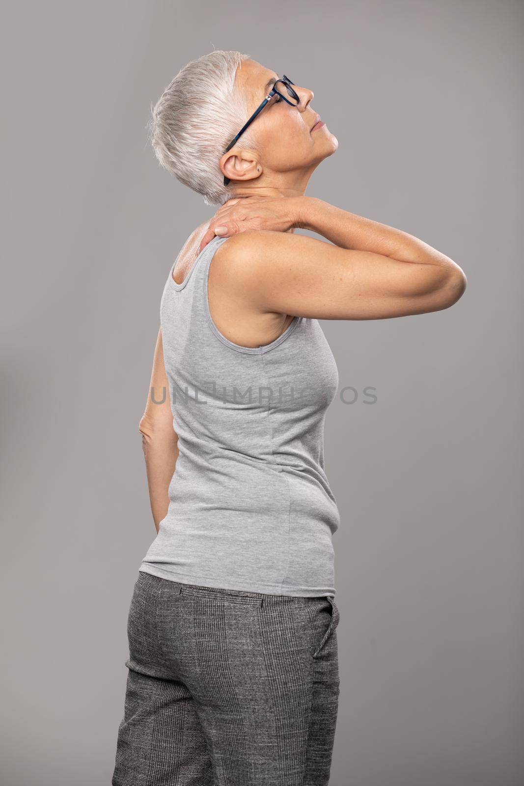 Backache pain in back, senior old woman with short gray hair and body and spinal muscle problems