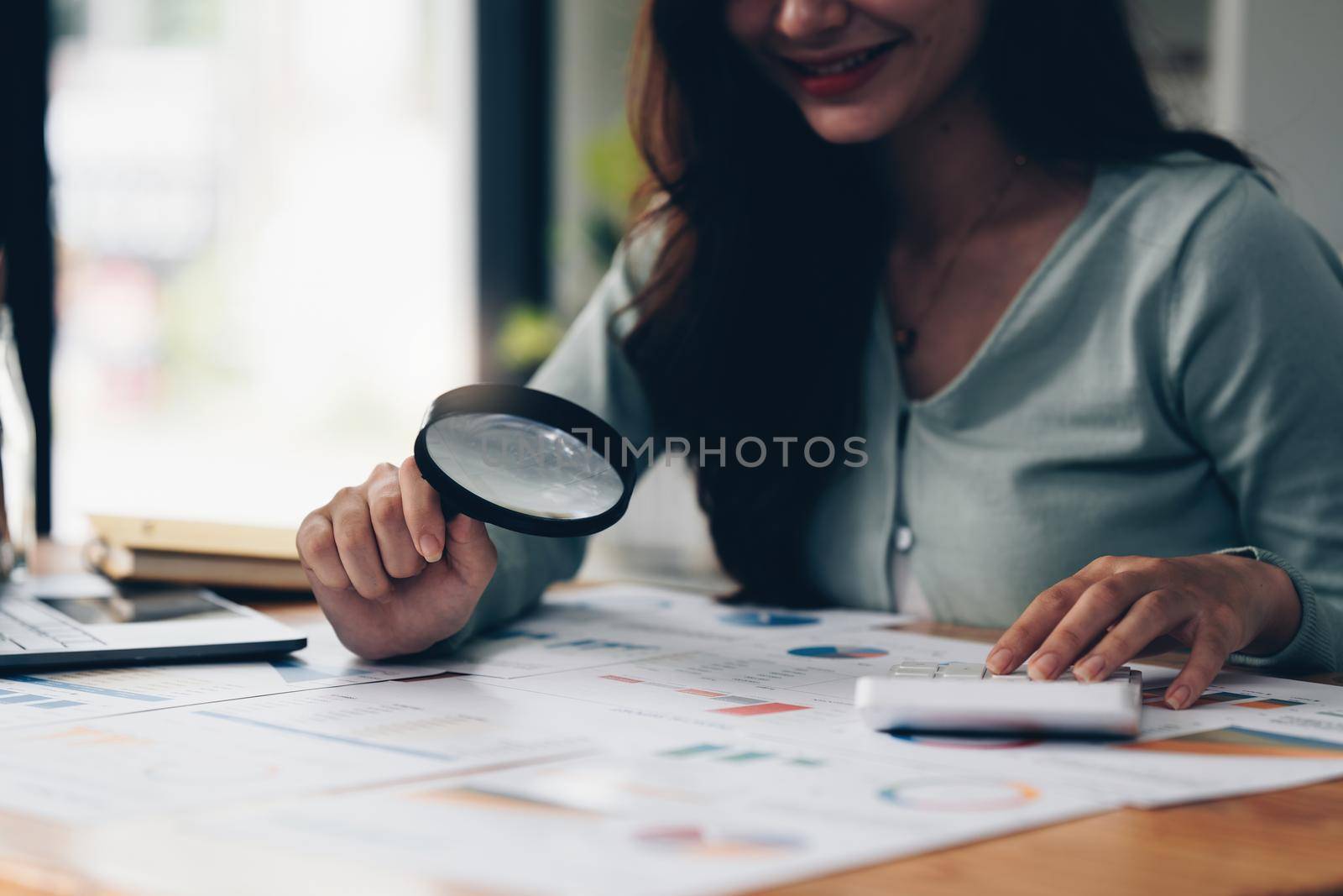 Portrait of Business woman using magnify to audit the company's financial results and budget. Account Audit Concept. by itchaznong