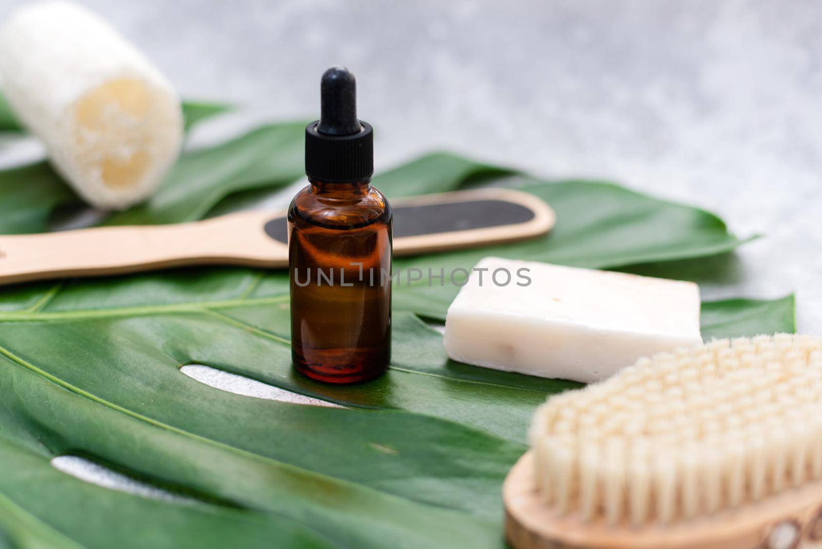 Natural cosmetics for bathing on the background of a palm leaf. Body moisturizing soap, serum and oil, loofah loofah and drainage brush.