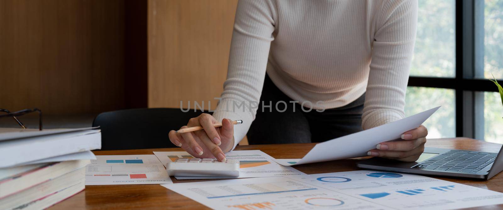 accountant, Auditor, Self-Employed, Finance and Investment, tax calculation and budget, Asian female entrepreneur using a calculator to calculate. Company business results document