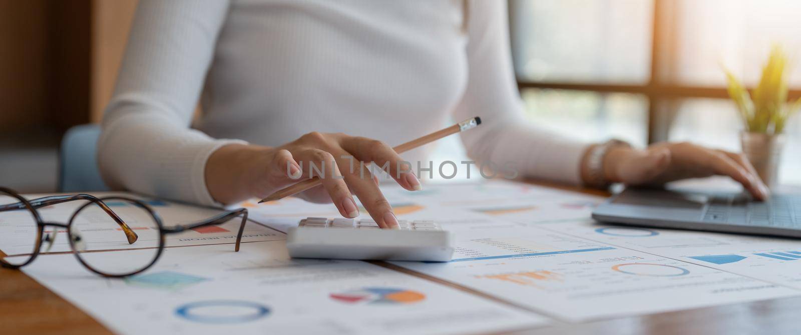 Businesswoman using calculator for analysis maketing plan, Accountant calculate financial report, computer with graph chart. Business, Finance and Accounting concept.