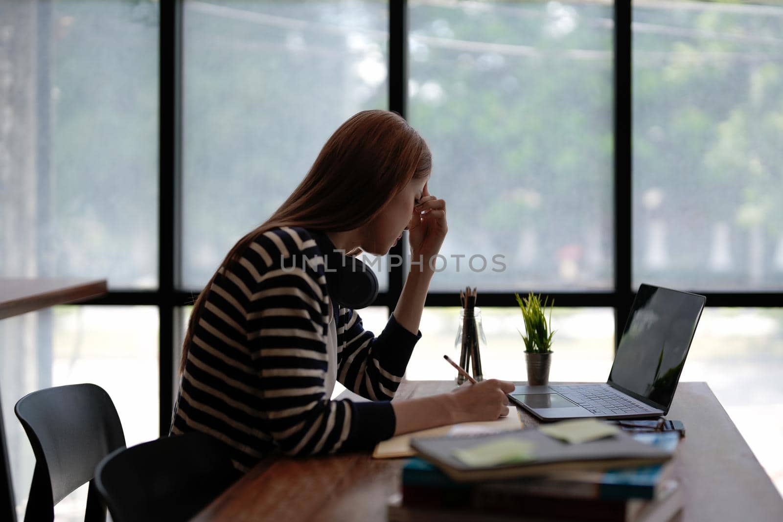 Stressed Asian woman cover her face with hand and feel upset from work in front of laptop computer on desk at office,Stress office lifestyle concept