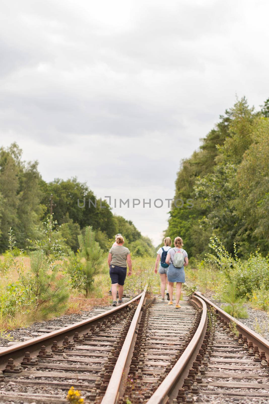 a group of tourists travelers in summer clothes walk along the old railway by KaterinaDalemans