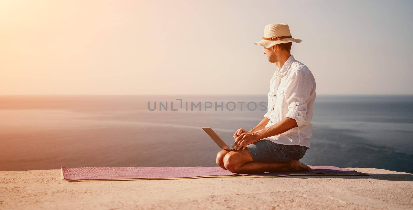 freelancer businessman working remotely on laptop at the beach near the sea