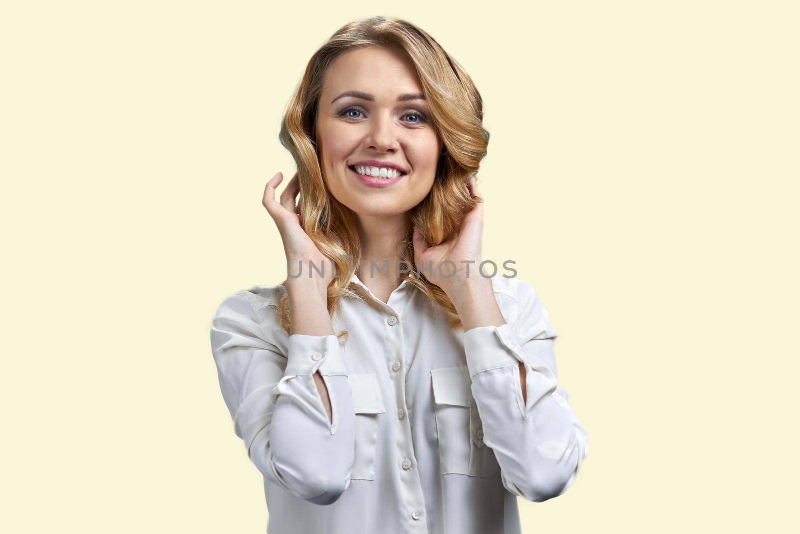 Pretty smiling blonde woman touching her hair and looking at camera. Isolated on white background.