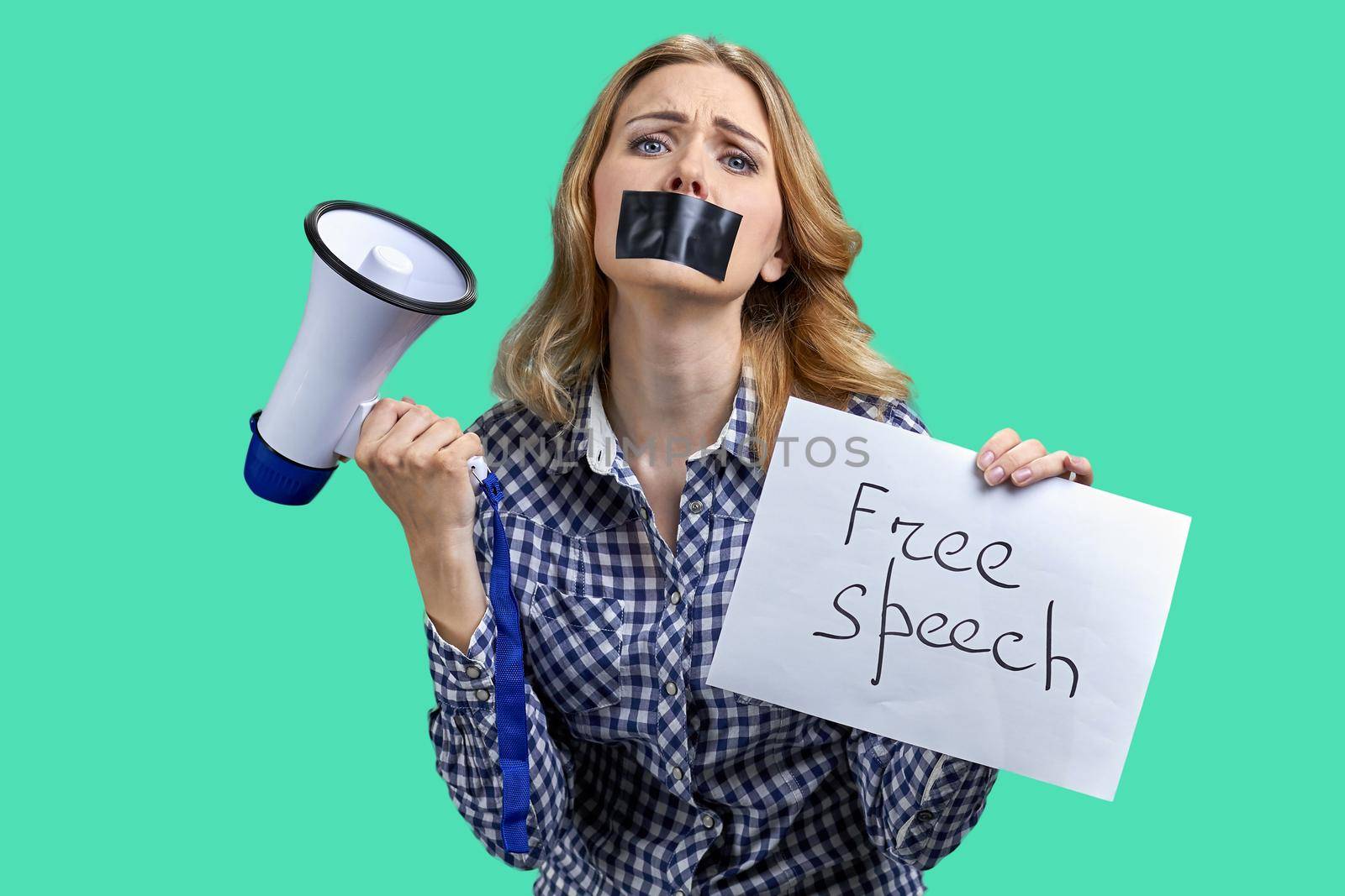 Stressed young woman protester with taped mouth holding banner with inscription Free speech. by super_picture