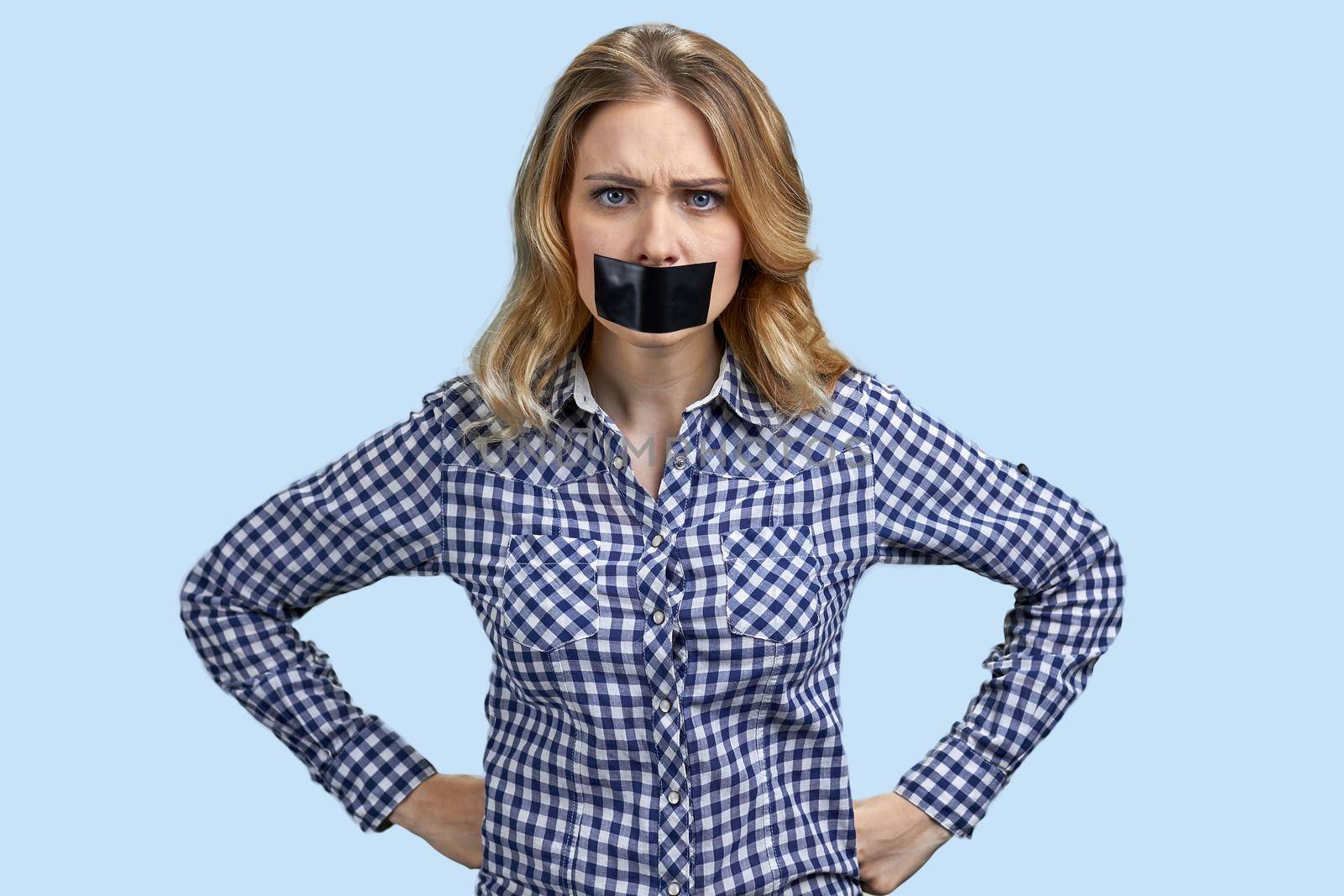 Irritated angry young woman with mouth covered with tape. Policy and human rights.
