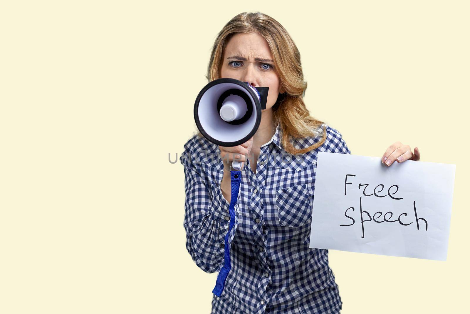 Upset woman protester with adhesive tape over mouth trying to speak in megaphone. Isolated on white background. Free speech.