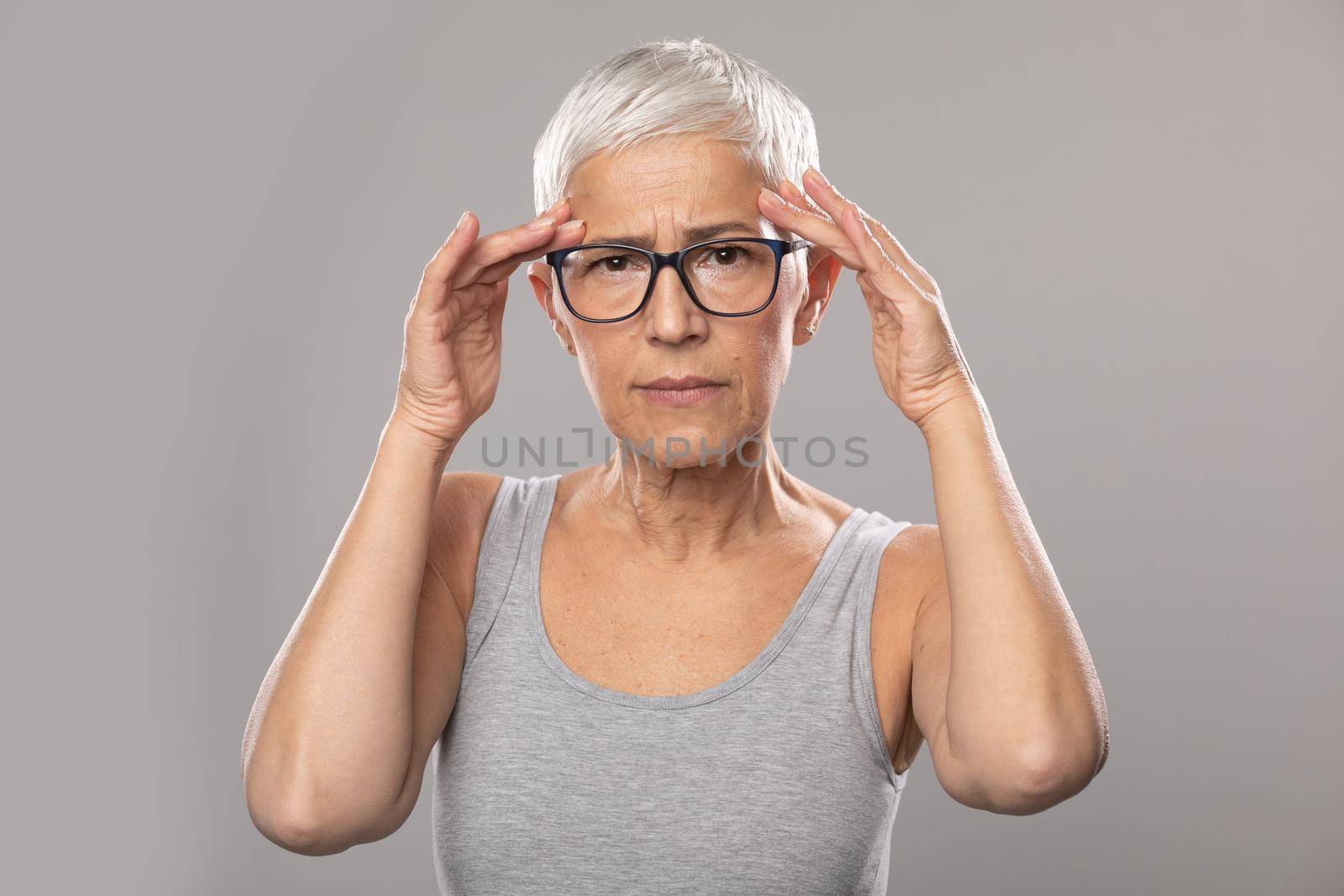 Headache migraine. Worried expression. Senior old woman with short gray hair and glasses show headache problems, healthcare and medicine concept