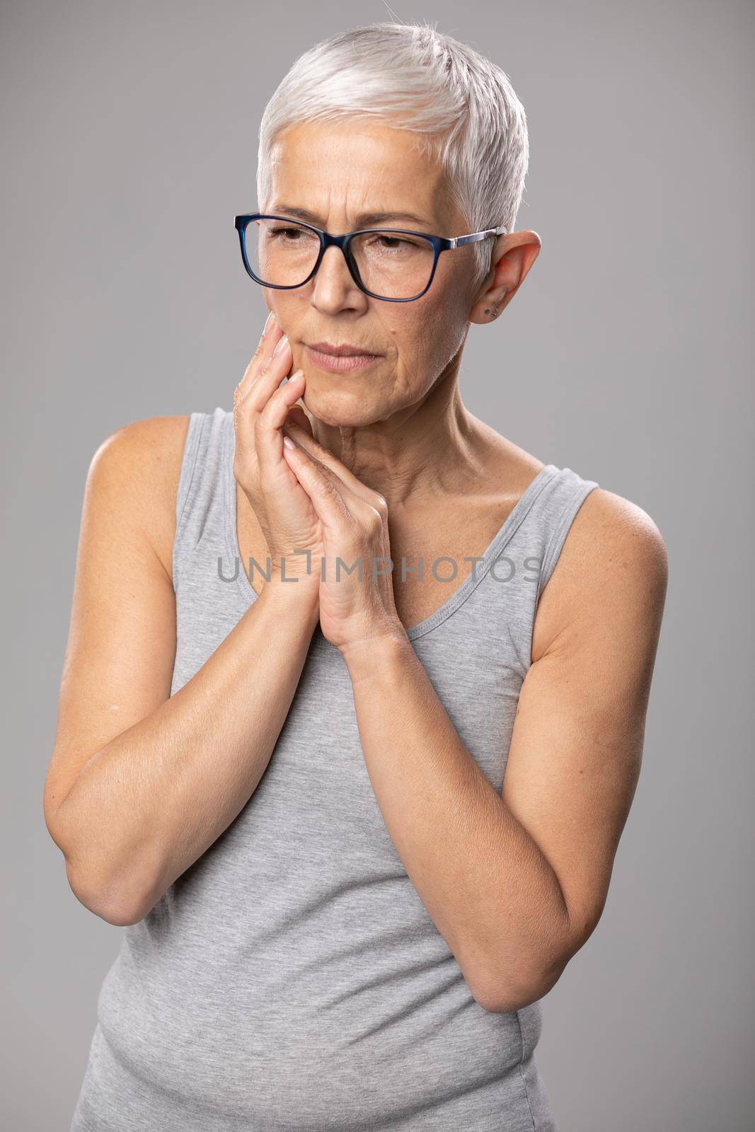 Toothache. pain tooth in mouth, old woman with short gray hair and tootache problems. Worried expression, healthcare and medicine concept