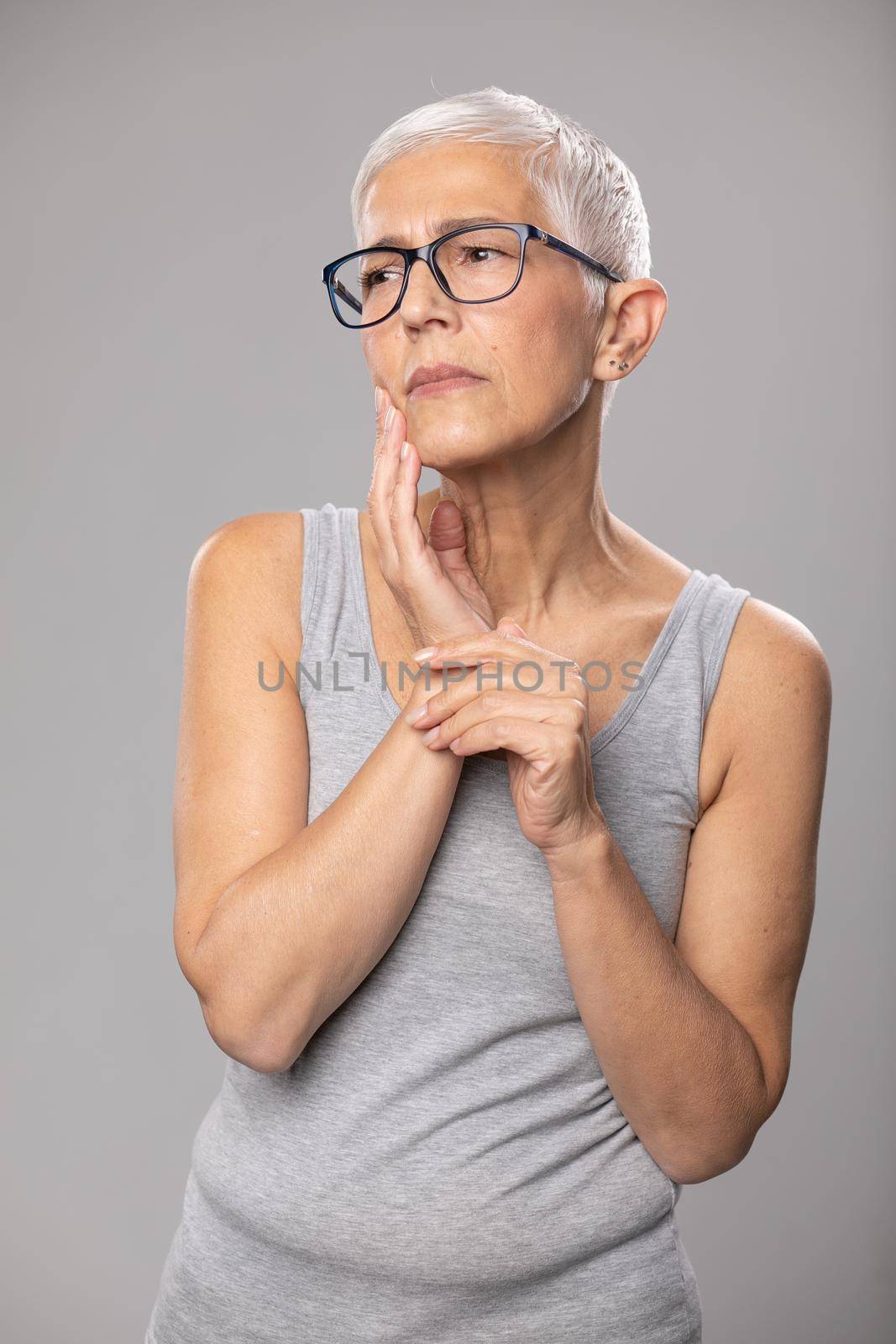 Senior woman with worried expression short gray hair and tootache problems by adamr