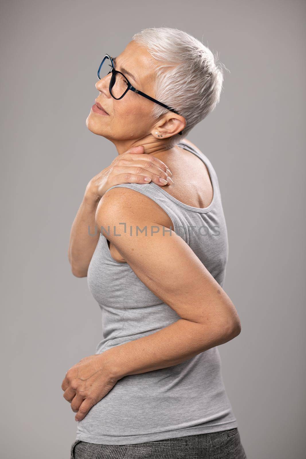Shoulder and neck and pain, senior old woman with short gray hair and body and spinal muscle problems by adamr