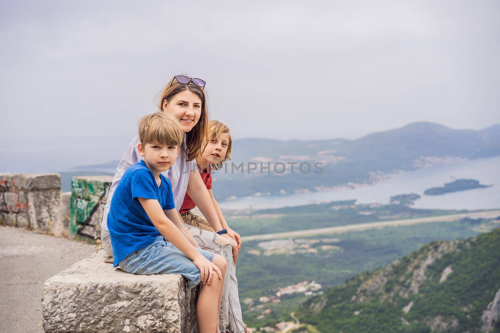 Mother and son travellers enjoys the view of Kotor. Montenegro. Bay of Kotor, Gulf of Kotor, Boka Kotorska and walled old city. Travel to Montenegro concept. Fortifications of Kotor is on UNESCO World Heritage.