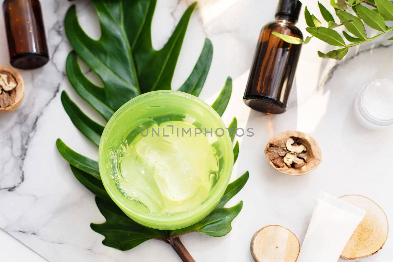 A beautiful composition with oil, aloe, soap and nuts. Bottles with spa cosmetic products on a palm leaf background, top view. Beauty salon procedures concept.