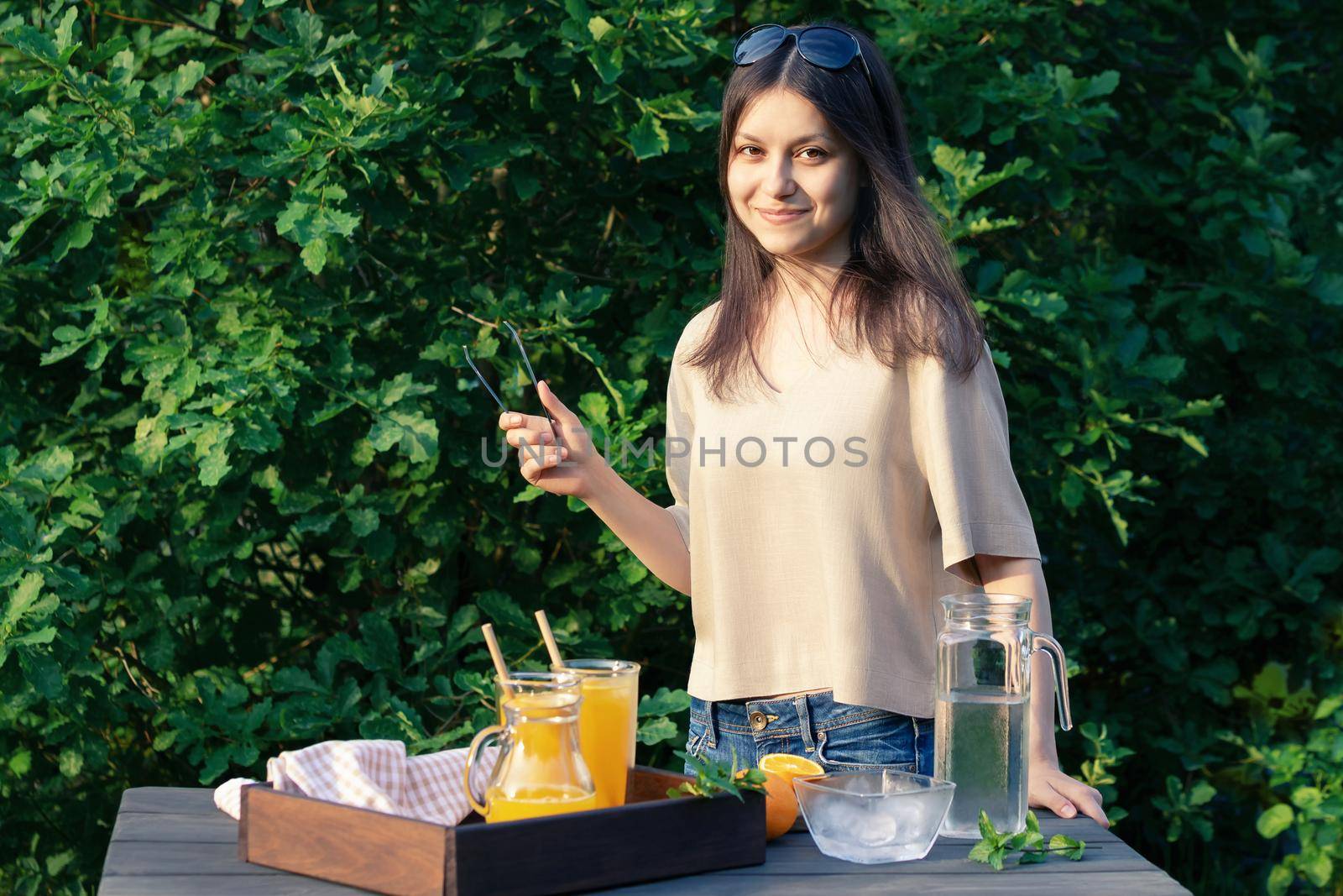 Girl cooking summer orange cocktail with mint and ice cubes outdoors, selective focus by galsand