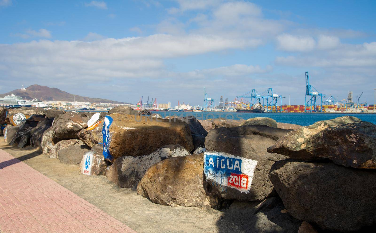 Paintings on stones in the harbour of Las Palmas de Gran Canary Spain, in the background you can see the industrial harbour