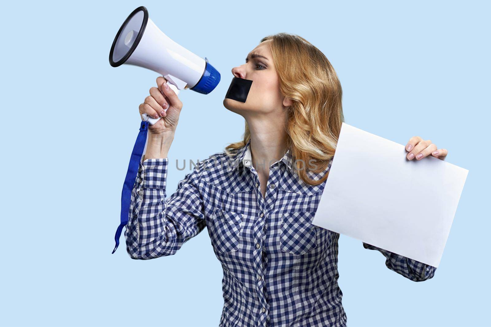 Female protester with taped mouth trying to speak in megaphone. Censorship concept.