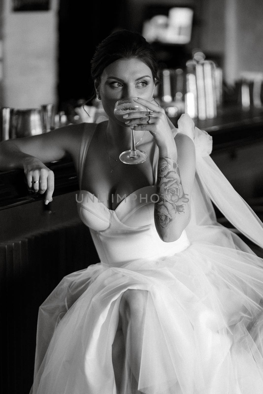 bride inside the cocktail bar at the bar in a bright atmosphere with a glass of drink