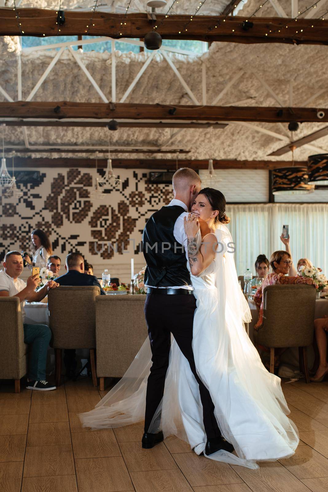 the first wedding dance of the bride and groom inside the restaurant hall in sunset light