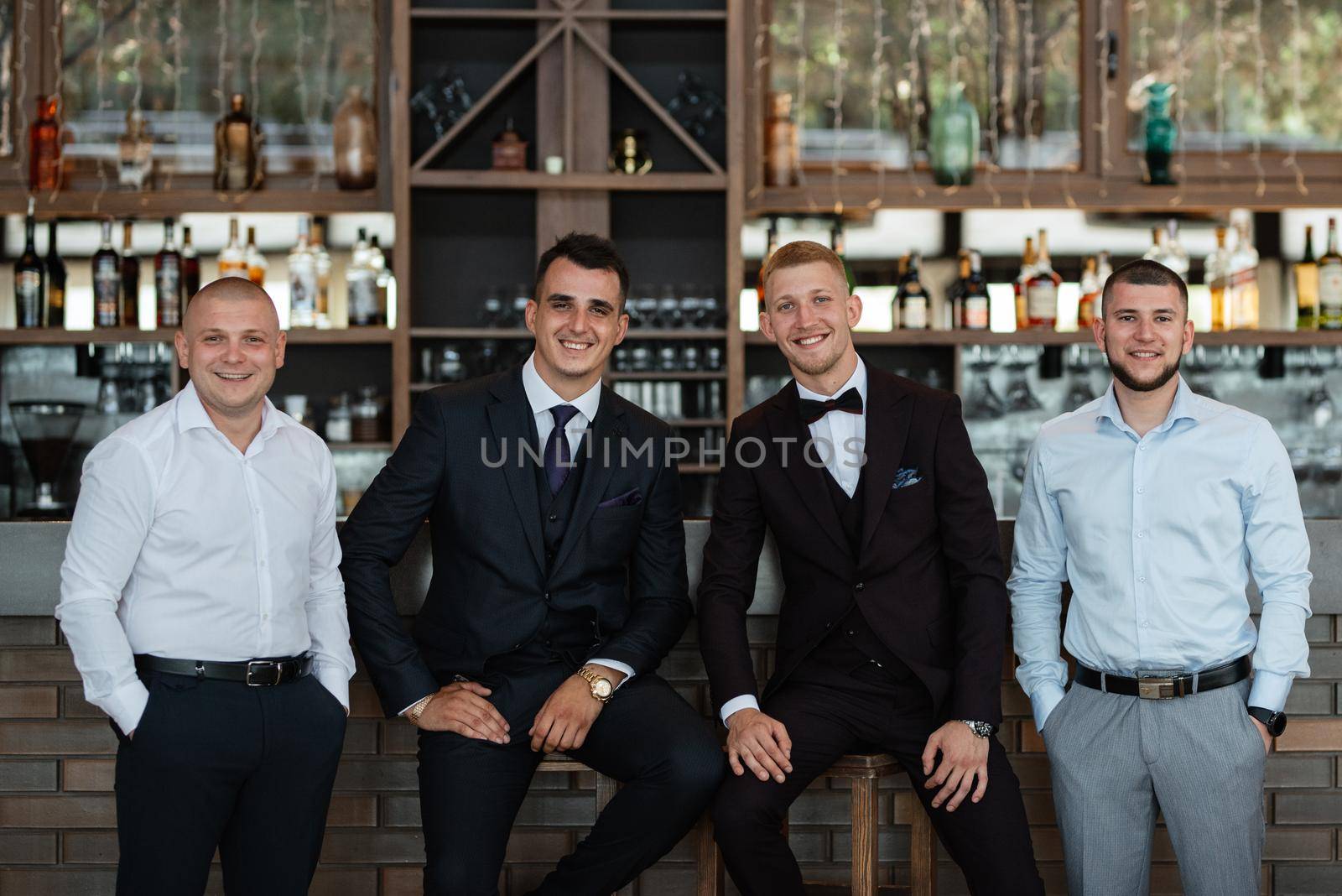 groom in a brown suit and his friends at the bar