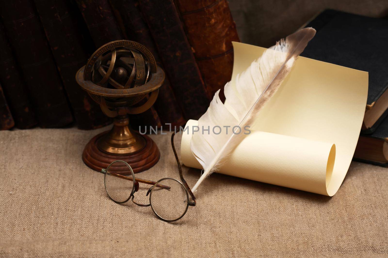 Still life with books and quill pen near scroll and old glasses