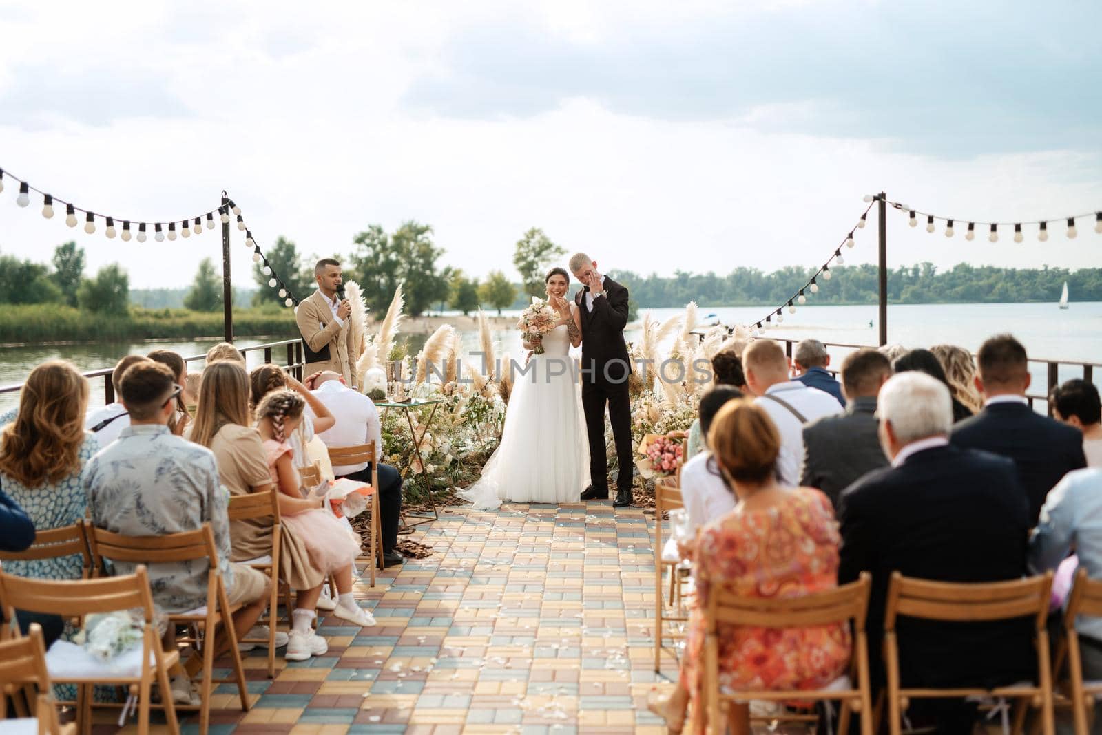 wedding ceremony on a high pier near the river with invited guests