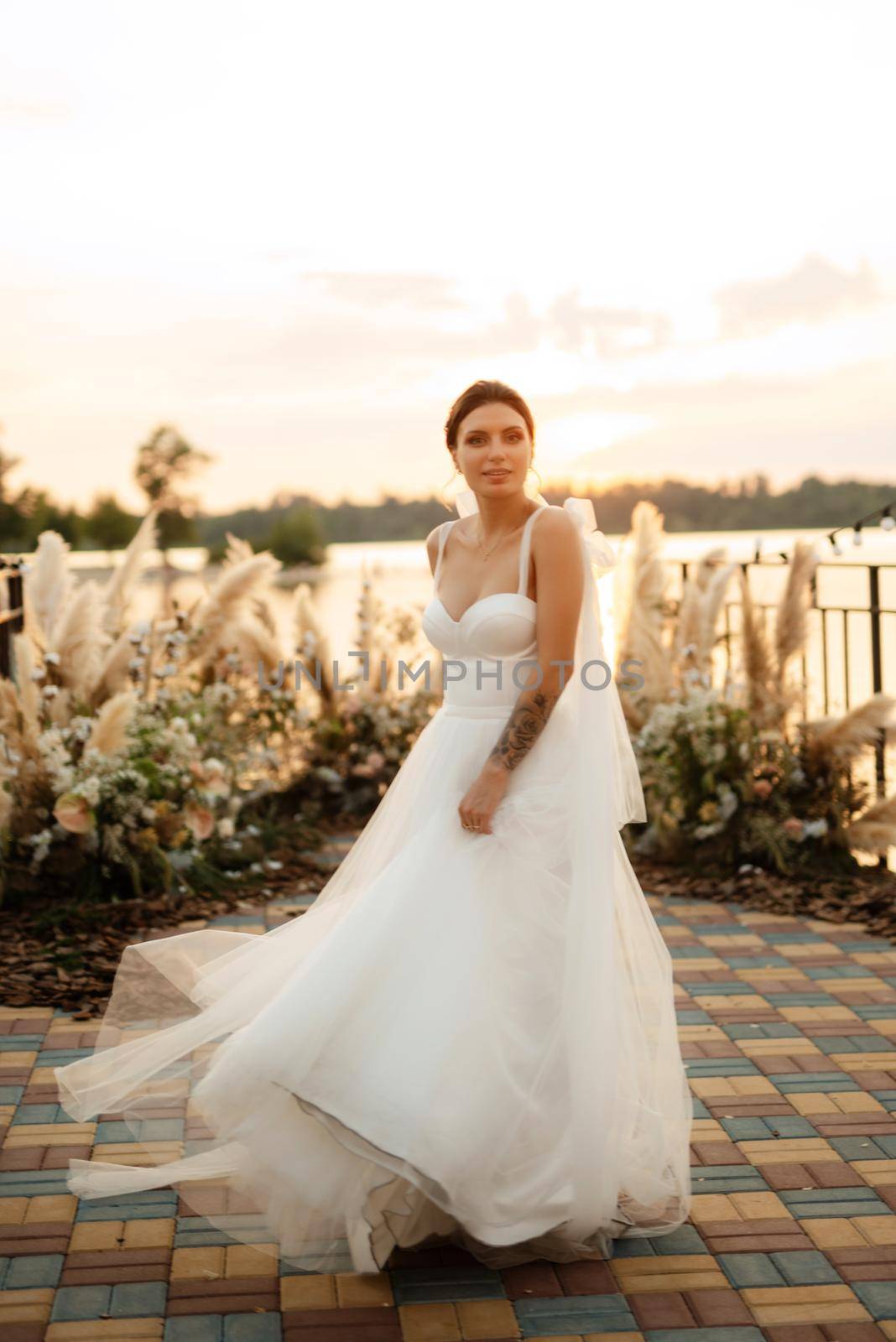bride against the background of a yellow sunset on a pier near the river