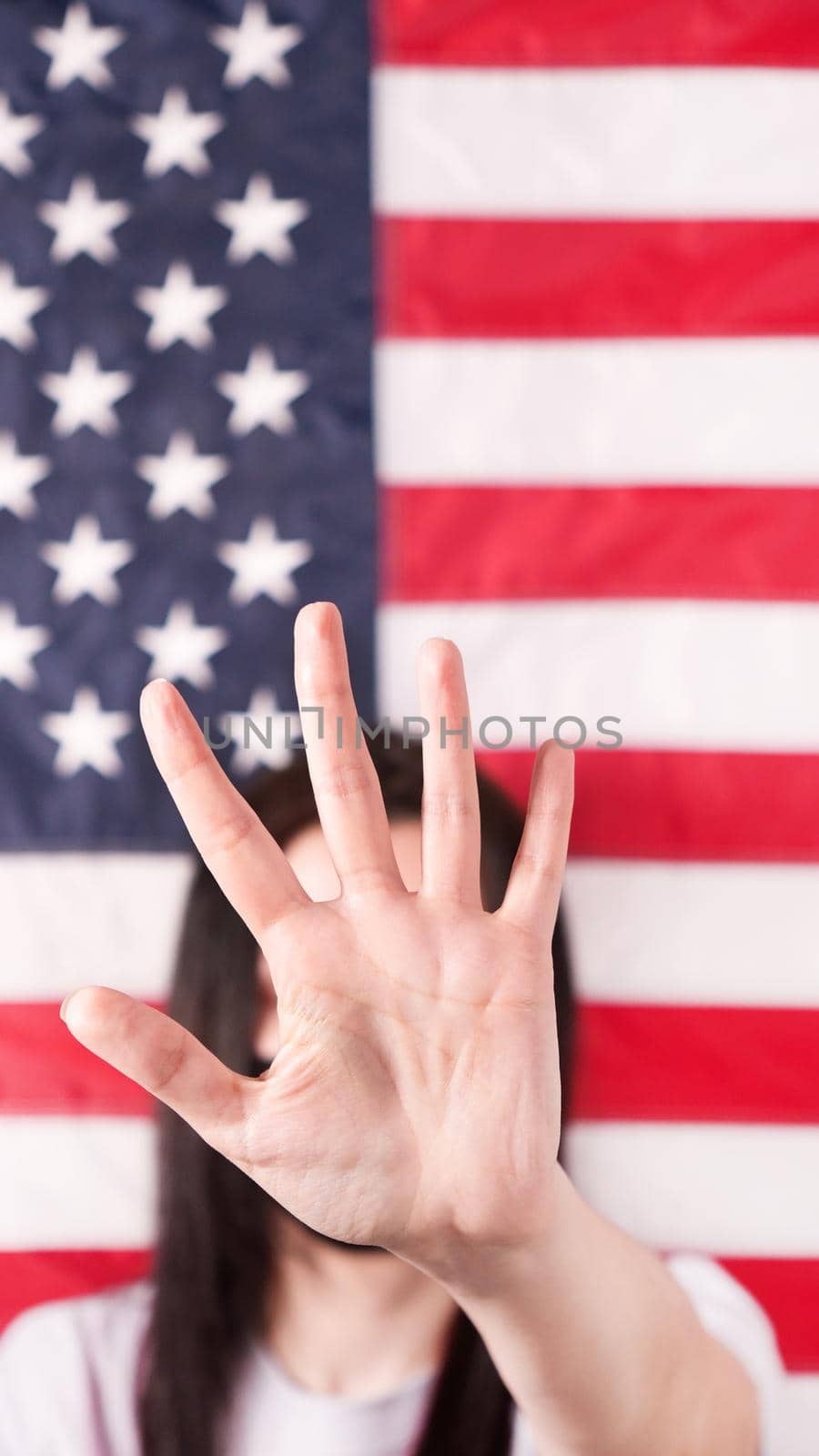 Young woman stretch out her palm to camera says stop abortion American flag on background, close up. Anti domestic violence, racism racial discrimination. Struggle for women rights, social problems. by JuliaDorian