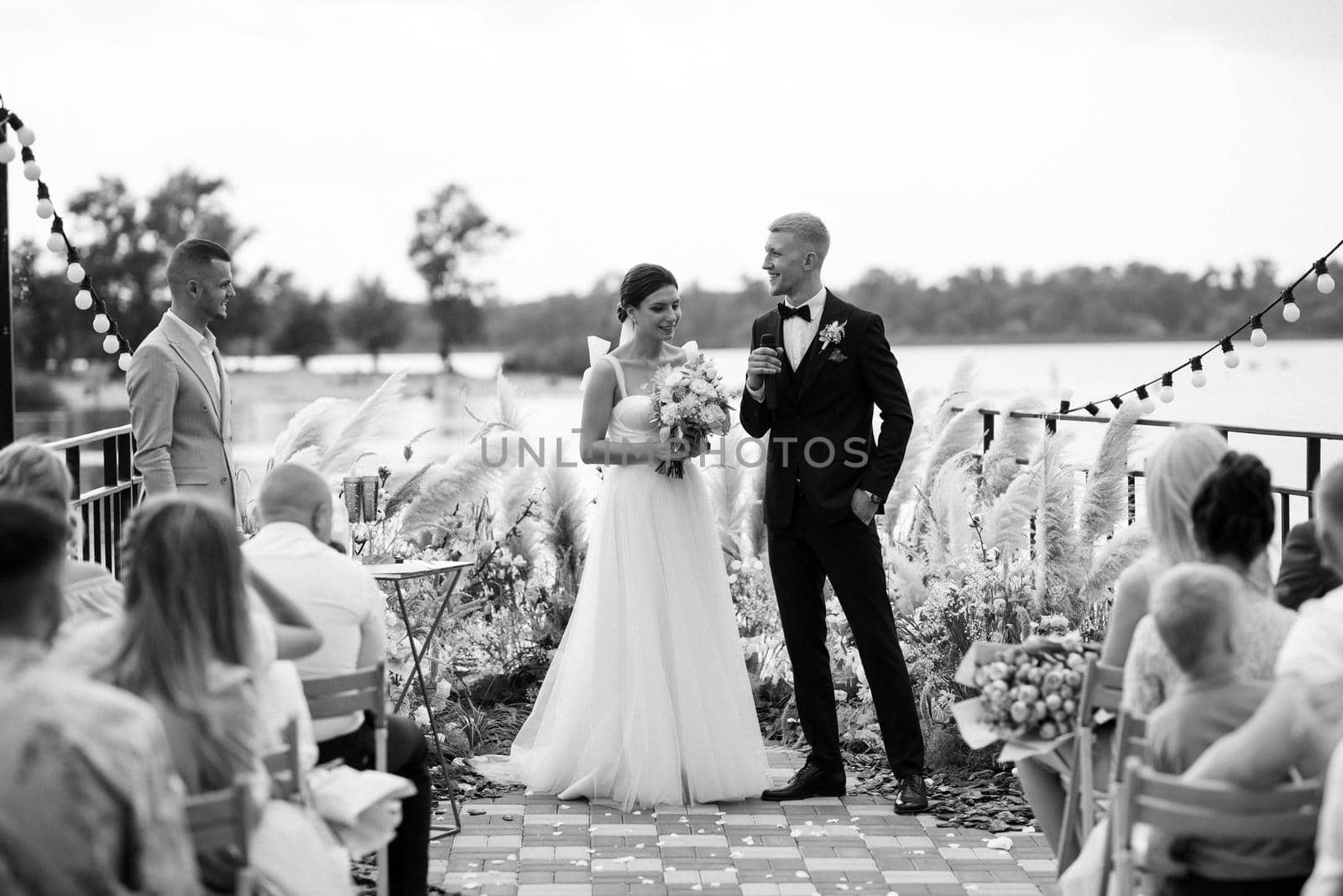 wedding ceremony on a high pier near the river with invited guests