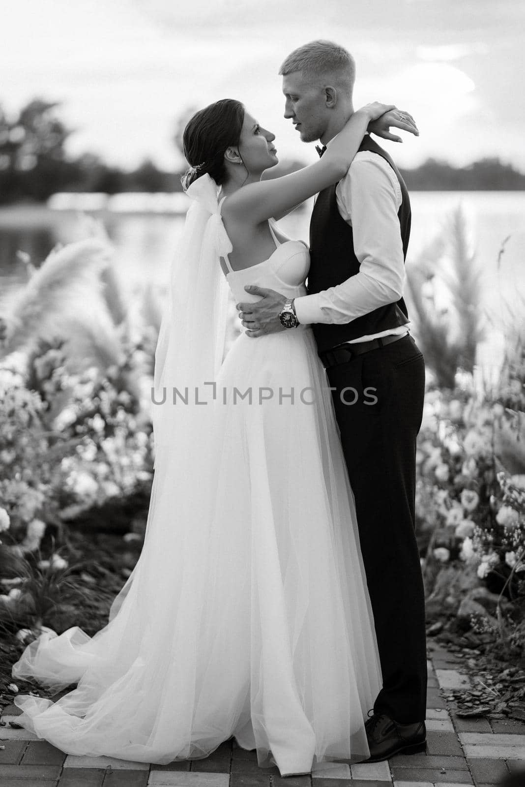 bride and groom against the backdrop of a yellow sunset on a pier near the river