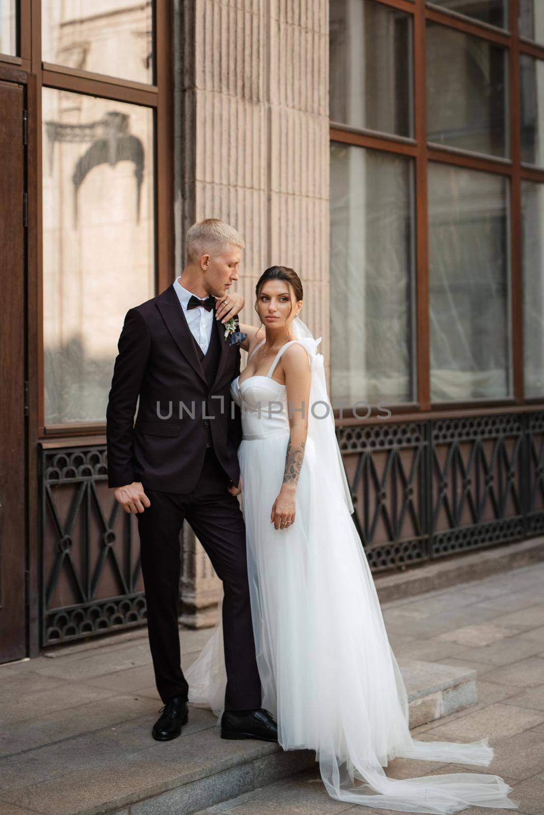 the groom in a brown suit and the bride in a white dress in an urban atmosphere