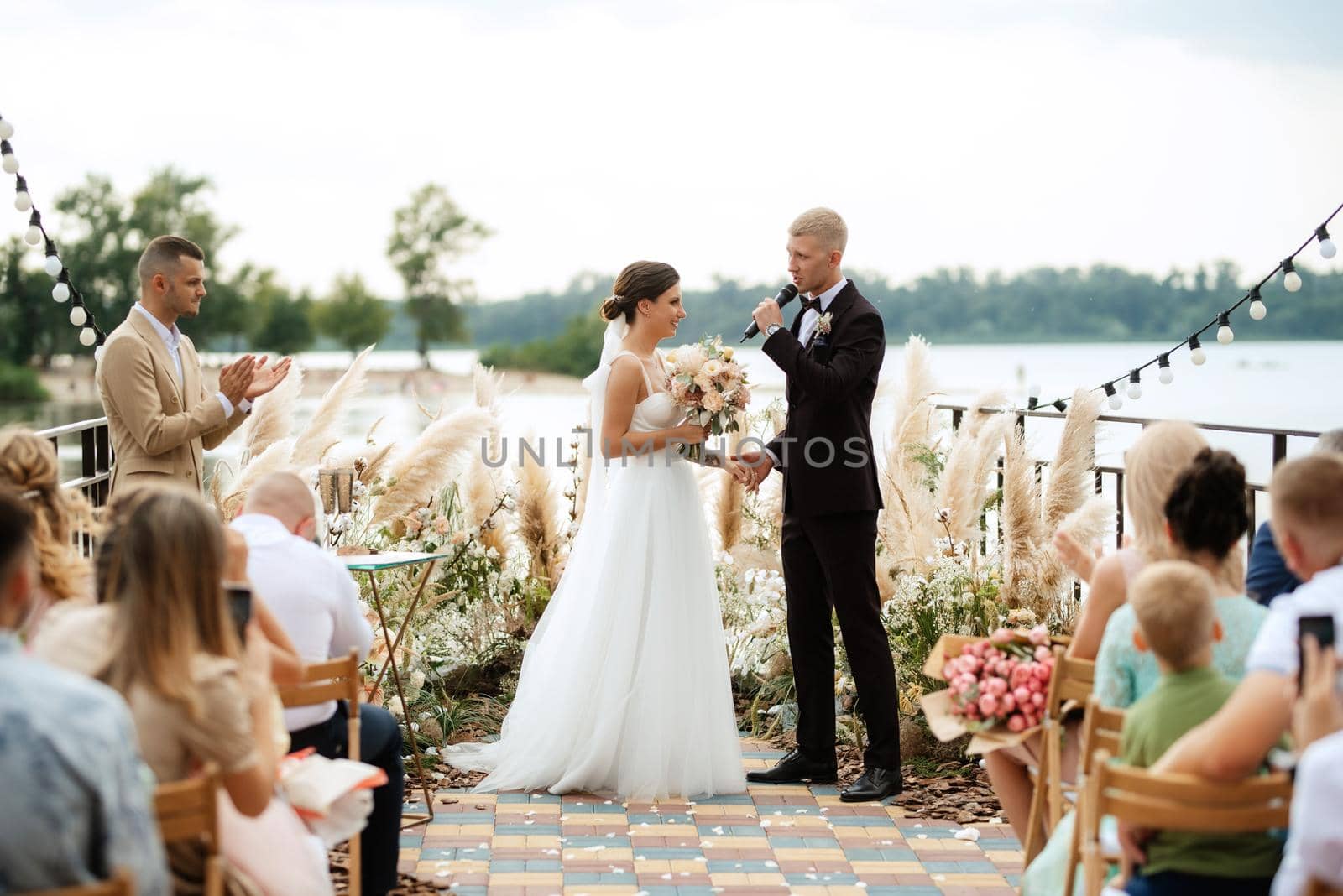 wedding ceremony on a high pier near the river with invited guests