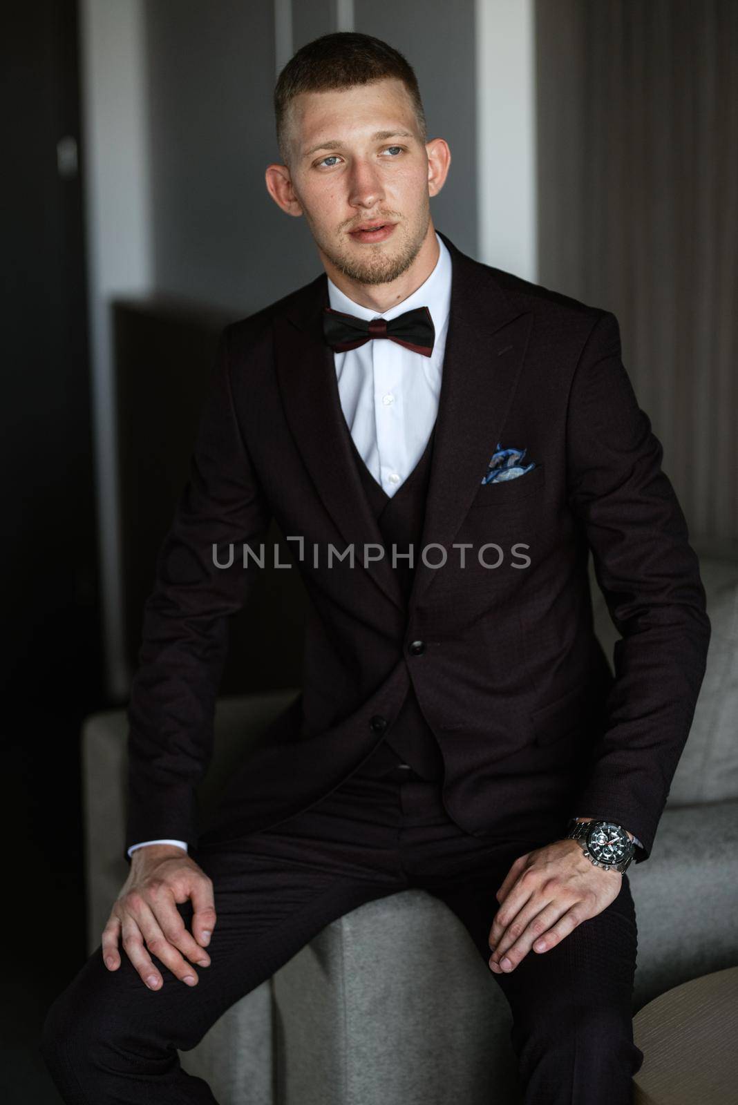 portrait of the groom in a brown three-piece suit with a bow tie on the wedding day